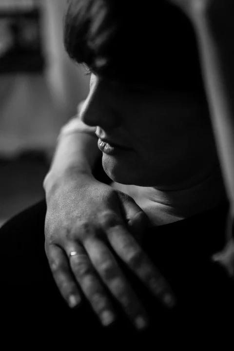 Silhouette einer jungen Frau mit der Hand einer Partner:in auf der Brust.